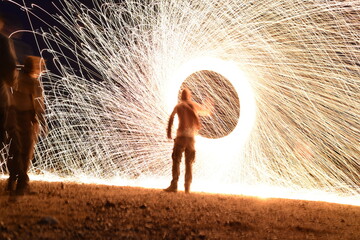 Iron wool circle drawing light fireworks. Burning Steel Wool spinning, Trajectories of burning sparks at night. Movement light effect, steel wool fire hoop. long exposure light painting, Pyrotechnic