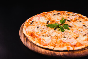 Italian pizza with mushrooms on a wooden board on a black background