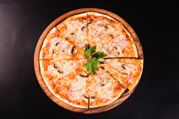 Italian pizza with mushrooms on a wooden board on a black background