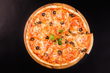 Pizza with olives and tomatoes on a wooden board on a black background