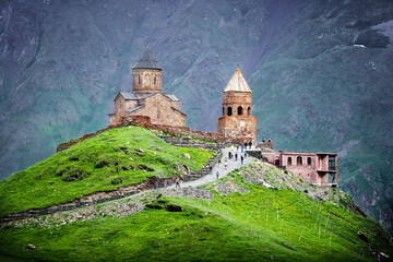 Kazbegi Mountains. View from the mountain to the city, the village of Stepantsminda. Green hills, mountain peaks. Travel in the mountains of Georgia.