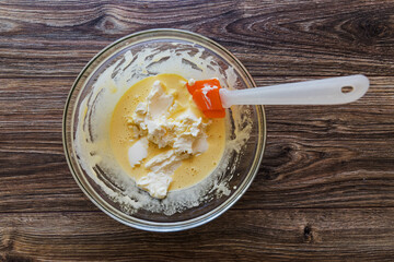 Adding mascarpone cheese to egg white with sugar, making tiramisu dessert cream. Large scoop for stirring in a bowl of mascarpone cheese with proteins.