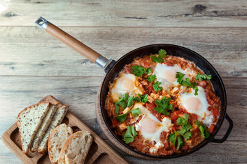 Shakshuka in a frying pan, poached eggs in spicy tomato sauce. Summer breakfast with eggs and tomato sauce.