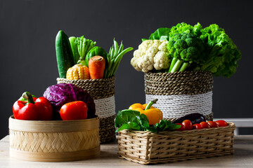 Various of fresh colorful vegetables in the wicker basket on wooden table