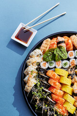 Minimal concept. Sushi rolls and chopsticks, isolated on blue background. Top view. Flat lay.