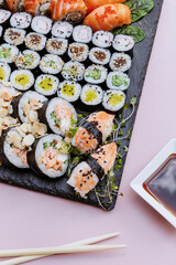 Minimal concept. Sushi rolls and chopsticks, isolated on pink background. Top view. Flat lay.