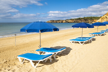 Scenic golden cliffs with umbrella and sunbathing in the Praia do Vau beach in Portimao, Algarve, Portugal