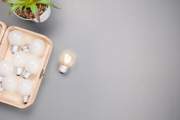 A small light bulb glowing outside the group in the box on gray background, success and creative idea concept with copy space