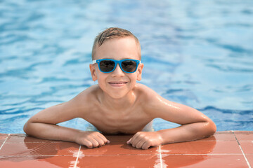 Boy in sunglasses in the pool. Summer vacation of a child in the pool.