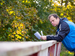 Man reading letter and leaning on the railing, worried and sad