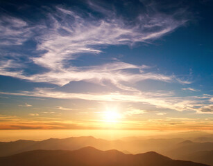 Silhouettes of mountains on background of majestic clouds on sunset sky shine