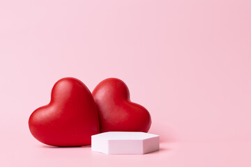 Pink podium with red heart on pastel background to show cosmetic products. Minimal romantic backdrop with stand for branding and presentation on Valentine's Day.