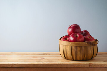 Red apples in basket on wooden table with copy space. Kitchen counter decoration mock up for design