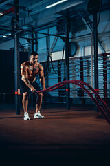 Young man, muscled athlete, bodybuilder training alone at sport gym, indoors. Concept of sport, activity, healthy lifestyle