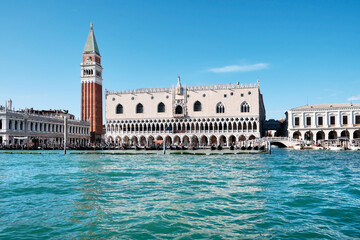 Fototapeta na wymiar Doge's palace and Campanile on Piazza di San Marco, Venice, Italy with reflection. View from passing vaporetto boat, with sea water of Venice Lagoon in front.