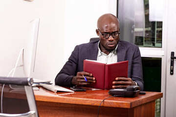 Serious adult businessman is checking the notes in his diary in the office.