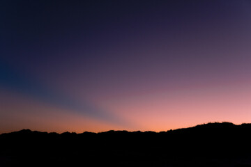 colorful purple and salmon-colored sky  with the silhouette of a beach
