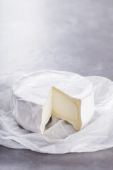Camembert on a gray cement background. Soft cheese with white mold on parchment paper. Copy space. Top view