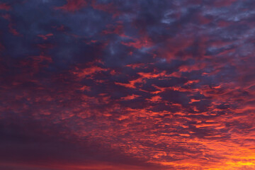 Epic dramatic sunrise, sunset orange red pink clouds in sunlight on blue sky background texture