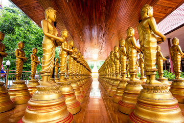 Fototapeta premium Several Buddha images in the posture of giving alms lined up on a pavilion at Wat Nakhon Chum Yai, Ratchaburi Province, Thailand.