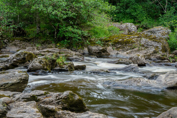 Naklejka na ściany i meble Water flowing over rocks in a river in Scotland