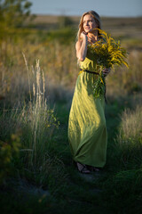 Obraz premium A young herbalist in love with a bouquet of herbs strolls romantically through the meadows.