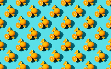 Seamless fruit pattern of fresh orange slices on blue background. Top view. Copy Space. Pop art design, creative summer concept. Half of citrus in minimal flat lay style.