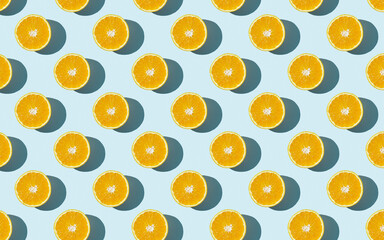 Seamless fruit pattern of fresh orange slices on blue background. Top view. Copy Space. Pop art design, creative summer concept. Half of citrus in minimal flat lay style.