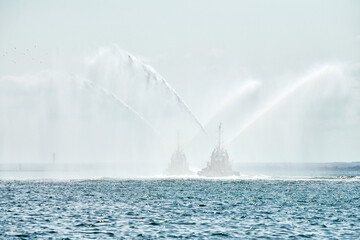 Tug boats spraying jets of water, demonstrating firefighting water cannons, fire boats spraying foam