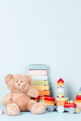 Kids toys collection. Teddy bear, wooden train, rainbow color xylophone and baby toys on light blue...
