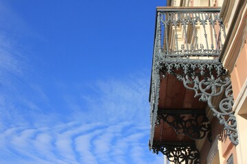 beautiful openwork balcony against the sky, decorated with wavy clouds - obrazy, fototapety, plakaty