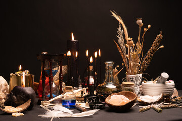 Witchcraft still life with black burning candles selective focus. Esoteric gothic and occult witch table for Halloween. Various magic objects and ritual arrangement. Gothic Halloween.