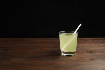 Lemonade or mojito cocktail with lemon and mint, cold refreshing drink or beverage with ice on rustic wood background. Homemade lemon and ginger organic drink, copy space.