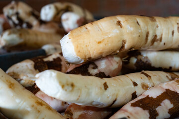 Peeled cassava in close-up detail with dark background and small pieces of peel