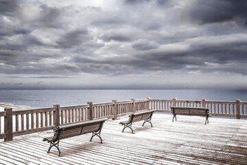 Fototapeta na wymiar Atardecer nublado en mirador frente al mar. Cielo dramático en Blanco y negro. Escena de paisaje nostálgica.