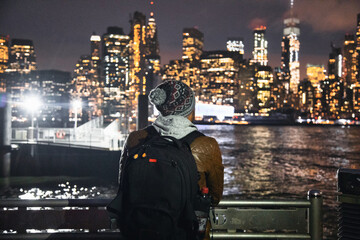 Fototapeta na wymiar Unrecognizable man looking at night city skyscrapers. American dream concept