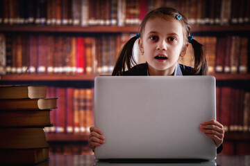 Education concept. Young beautiful child girl working  with laptop and reading books in library. Horizontal image. Copy space.