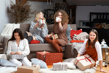 group of young attractive women have fun packing wrapping Christmas presents in a cozy home atmosphe