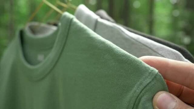 cotton t-shirts on hangers outdoor, clothes of various colors. sustainable fashion concept, eco fashion. textile and fashion industries, environmental problems, recycling, synthetic matherials