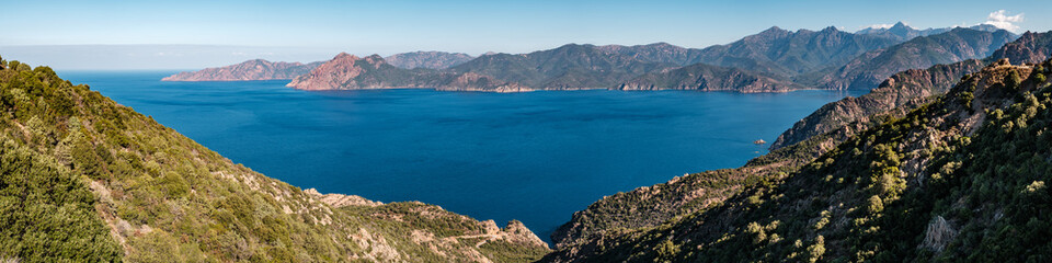 Fototapeta na wymiar Panoramic view of the Gulf of Porto on the west coast of Corsica with mountains including Paglia Orba and Monte Senino in the distance