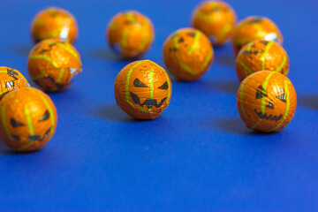 Jack o lantern pumpkins in a form of decorative beads or balls scattered on minimalistic blue background with copy space. Sweets, candies, trick-or-treats. Halloween celebration Oct. 31. Party treats.