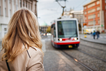 Woman waiting for tramway. Commuter looking at arriving tram in city. Public transportation