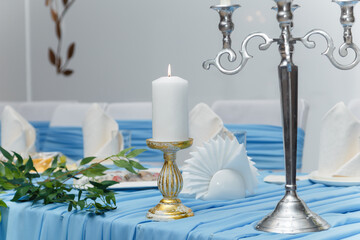 Naklejka premium Decorated blue wedding presidium, festive table for just married, event organization. Beautiful flowers and burning candles. Close up shot
