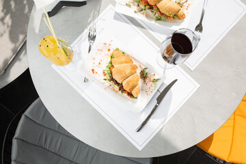 Two kinds of croissant sandwich with meat, tomatoes and lettuce salad and avocado on bright background. Continental style breakfast.