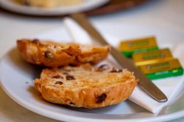Traditional toasted tea cake and butter on a white plate with selective intentional close focus