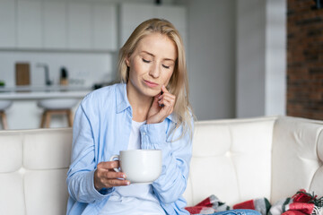 Woman with sensitive teeth holding cup of cold drink
