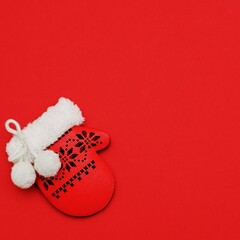 Festive decorative red christmas mitten on red background. Square Merry Christmas New Year greeting card. Flat lay with copy space. 