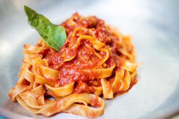 Tagliatelle with bolognese sauce with basil leaf.