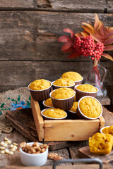 Pumpkin muffins with white chocolate and walnuts. Side view, wooden background. Red rowan