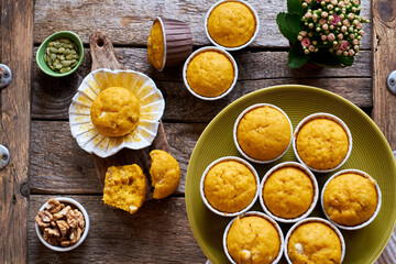 Pumpkin muffins with white chocolate and walnuts. Top view, wooden background.